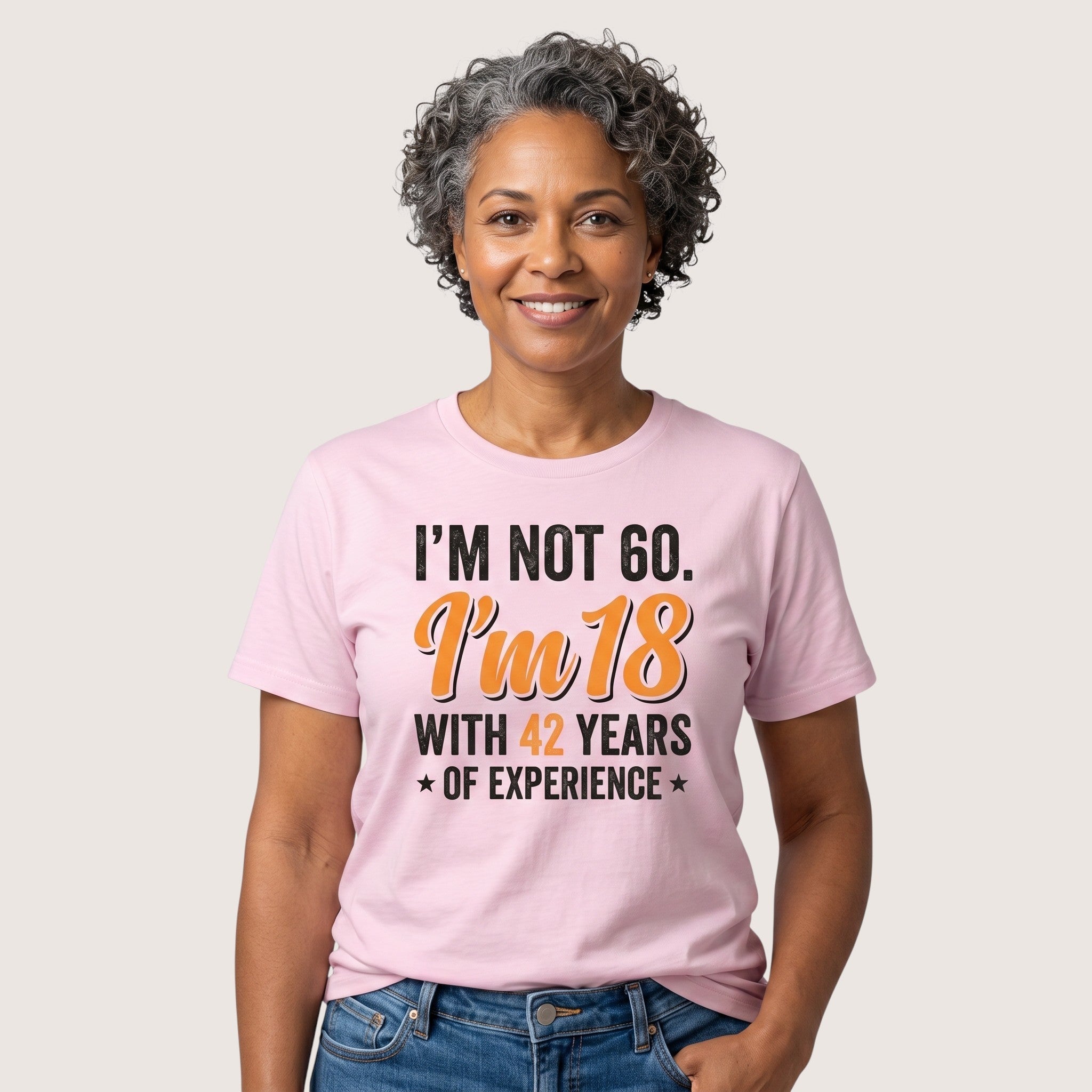 TrendyShift.Com light pink cotton t-shirt with humorous 60th birthday quote worn by a smiling woman with grey hair.